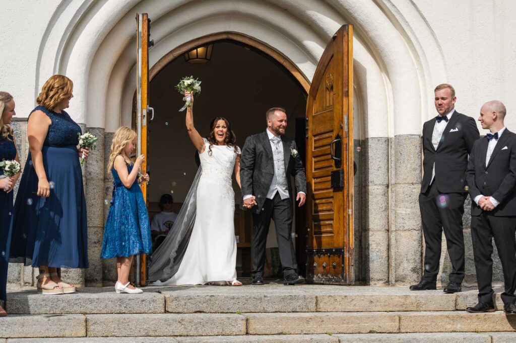 Brudparet på trappan i Nygift brudpar går ut ur Brudparet vid altaret i Trefaldighetskyrkan i Arvika tar emot gratulationer för bröllopsgästerna