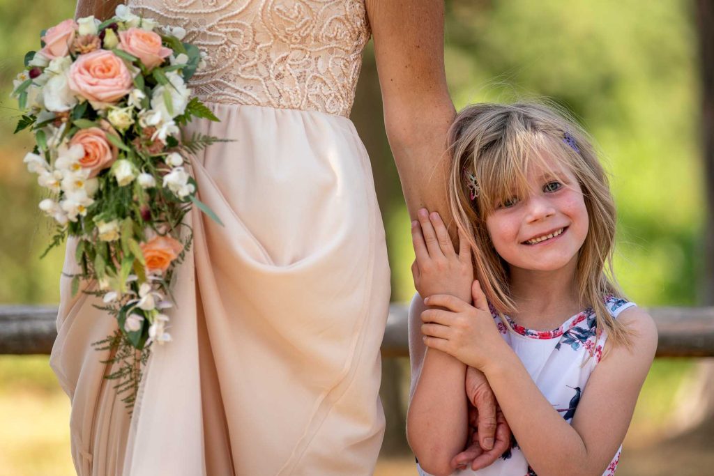 Liten flicka håller i brudens arm på bröllopsfest på Avelsbols hembygdsgård Arvika