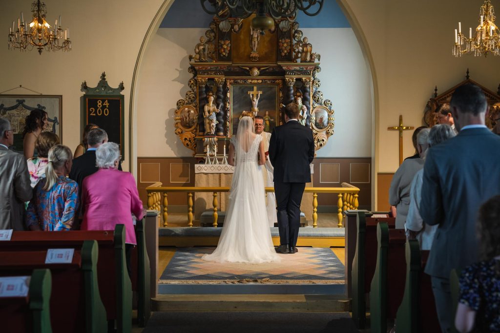 Brudgum och brud står vid altaret för vigsel i Skillingmarks kyrka.