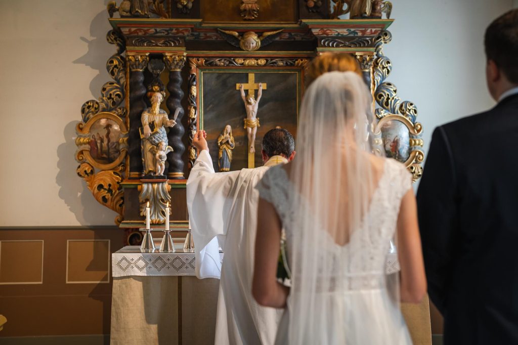 Prästen välsignar brudparet och håller upp vigselringarna i Skillingmarks kyrka.