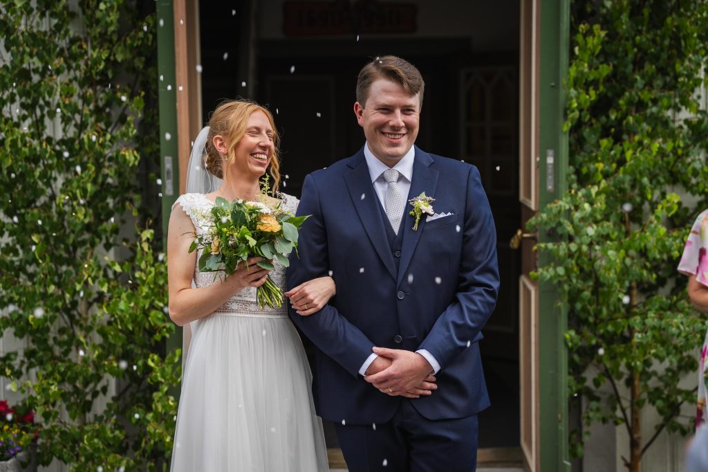 Brudparet blir gratulerade utanför Skillingmarks kyrka och bröllopsgästerna kastar ris på dem.