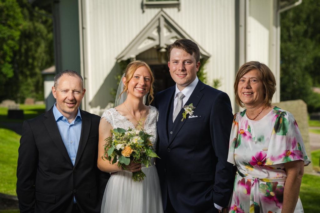 Porträtt av brudparet och föräldrar utanför Skillingmarks kyrka.
