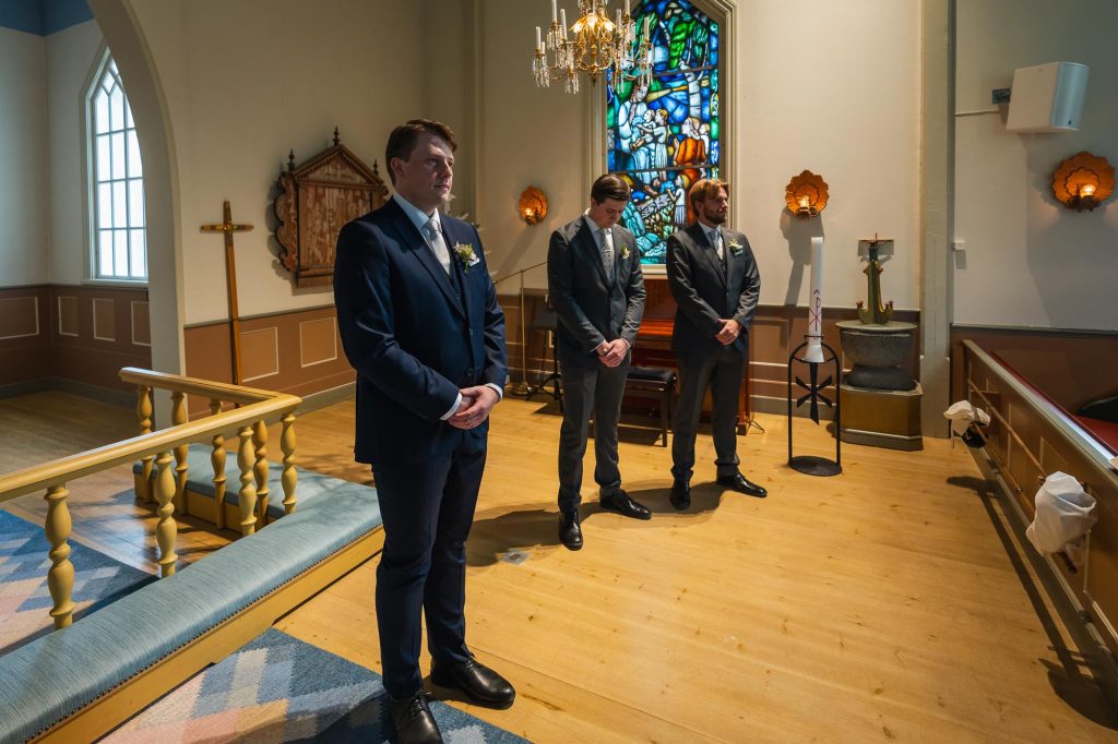 Brudgummen väntar på bruden vid altaret i Skillingmarks kyrka.