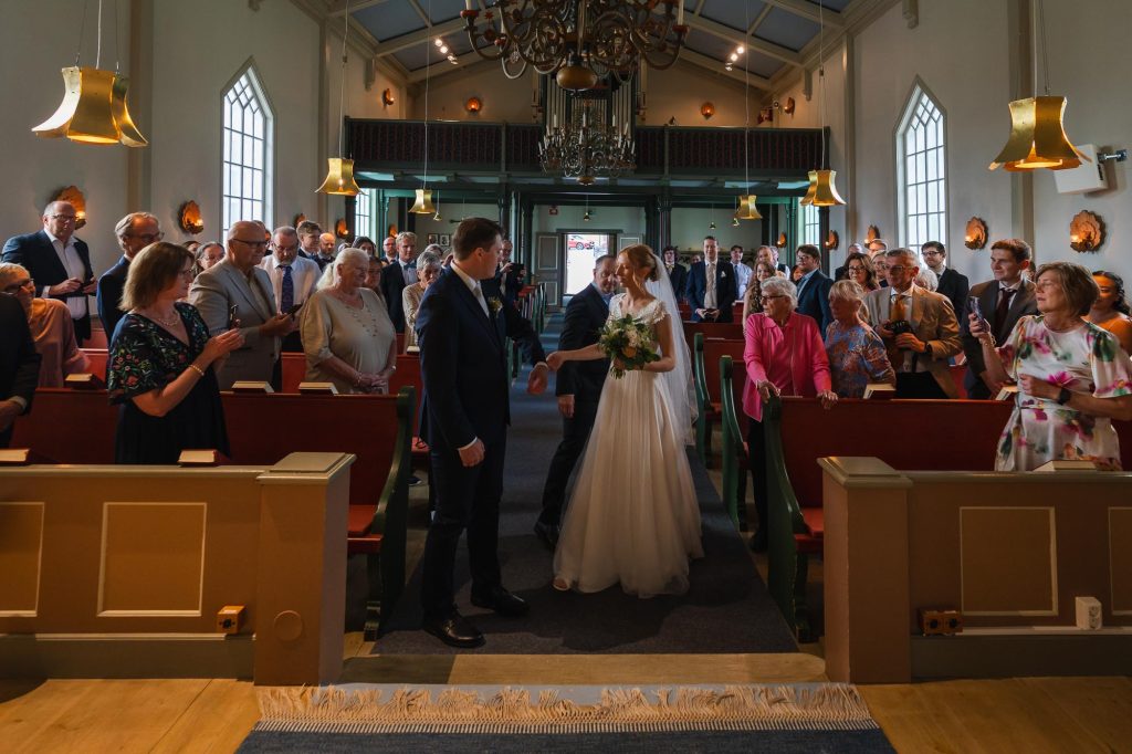 Brudens far lämnar över bruden till brudgummen i Skillingmarks kyrka.