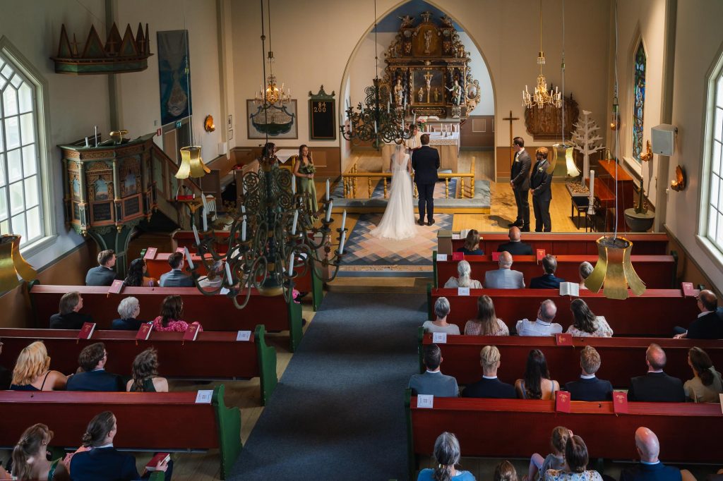Bild från läktaren av alla bröllopsgäster och bröllopspar under vigselakten i Skillingmarks kyrka.
