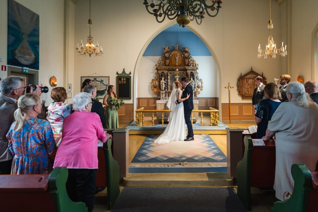 Brudparet kysser varandra framför altaret i Skillingmarks kyrka.