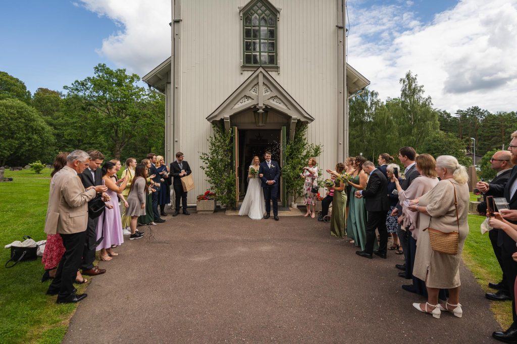 Brudparet blir gratulerade utanför Skillingmarks kyrka och bröllopsgästerna kastar ris på dem.