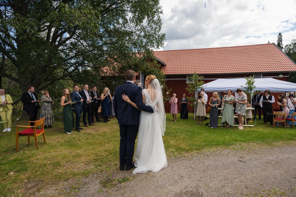 Brudparet skålar med bröllopsgästerna på Skillingmarks hembygdsgård.