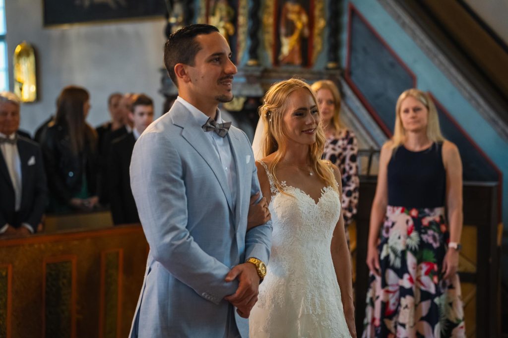 Brudparet hand i hand vid altaret i Mikaelikrykan i Arvika.