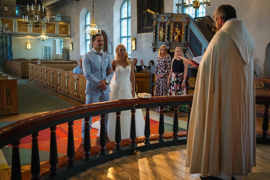 Brudparet hand i hand vid altaret i Mikaelikrykan i Arvika.