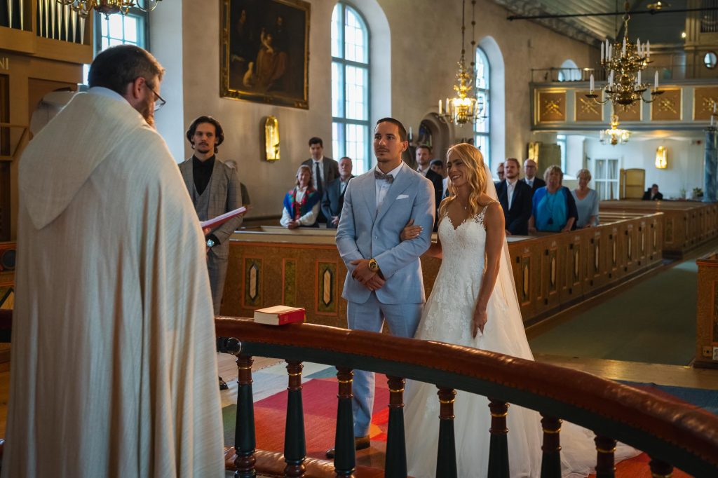 Brudparet hand i hand vid altaret i Mikaelikrykan i Arvika.