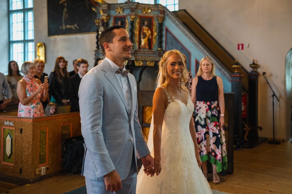 Lyckligt brudpar står framför altaret i Mikaelikyrkan i Arvika.