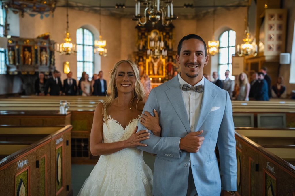 Brudparet går hand i hand nedför altargången i Mikaelikyrkan i Arvika.