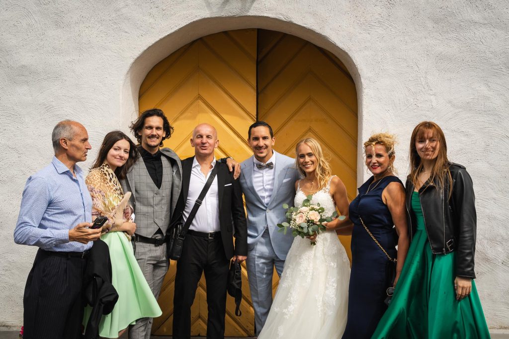 Gruppbild av brudpar och närmaste familj utanför Mikaelikyrkan i Arvika.