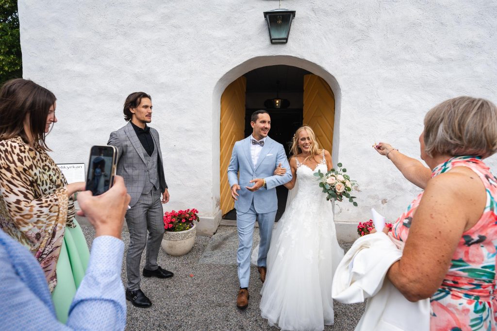 Bröllopsgästerna gratulerar det nygifta brudparet utanför Mikaelikyrkan i Arvika.