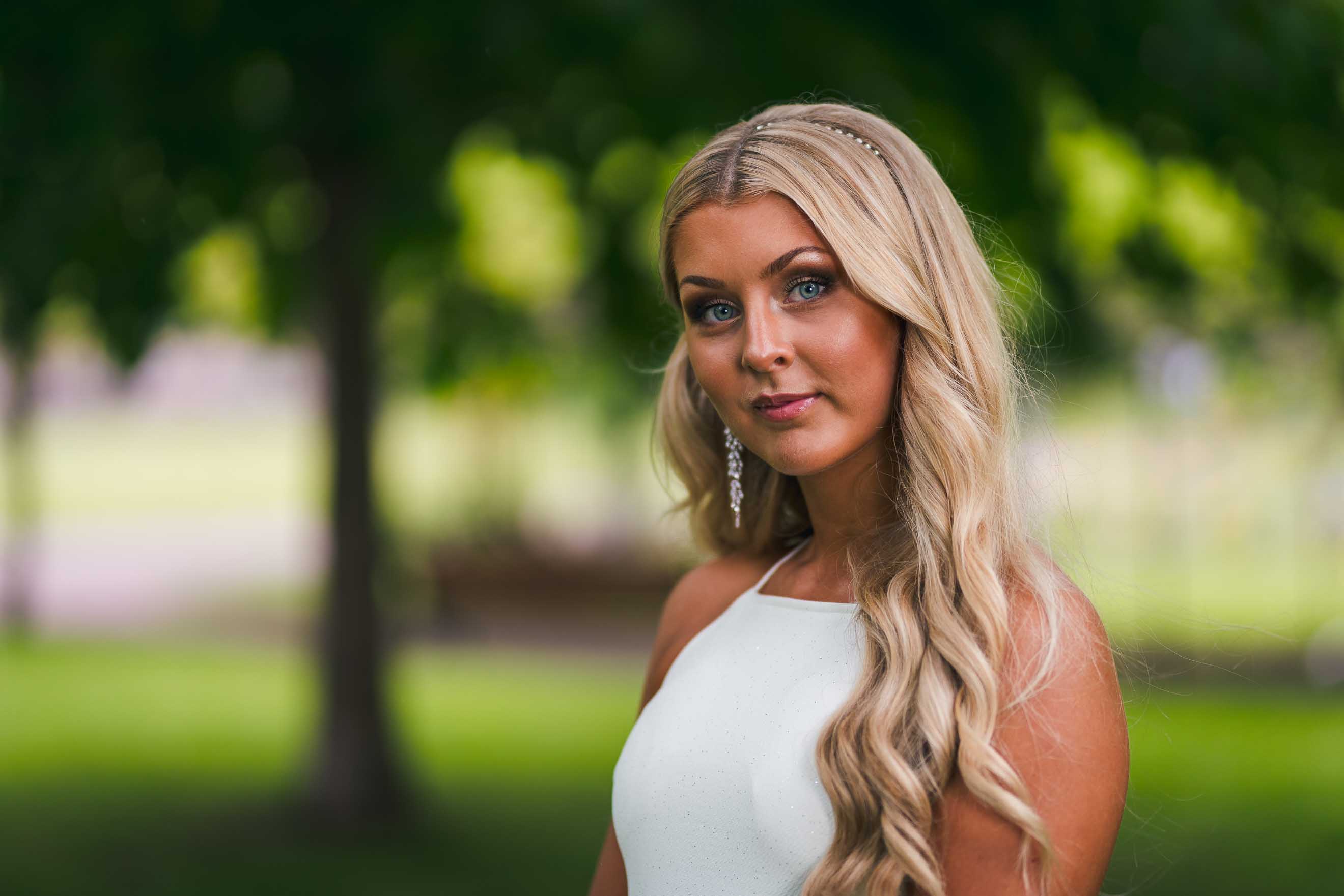 Porträtt av ung kvinna i vit klänning på studentdagen.