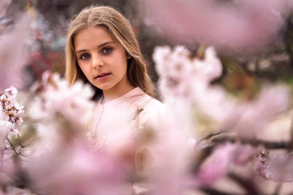 Porträtt av ung flicka som står mitt bland körsbärsblomstern.