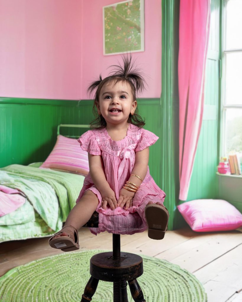 Liten flicka i rosa klänning sitter på en stol.