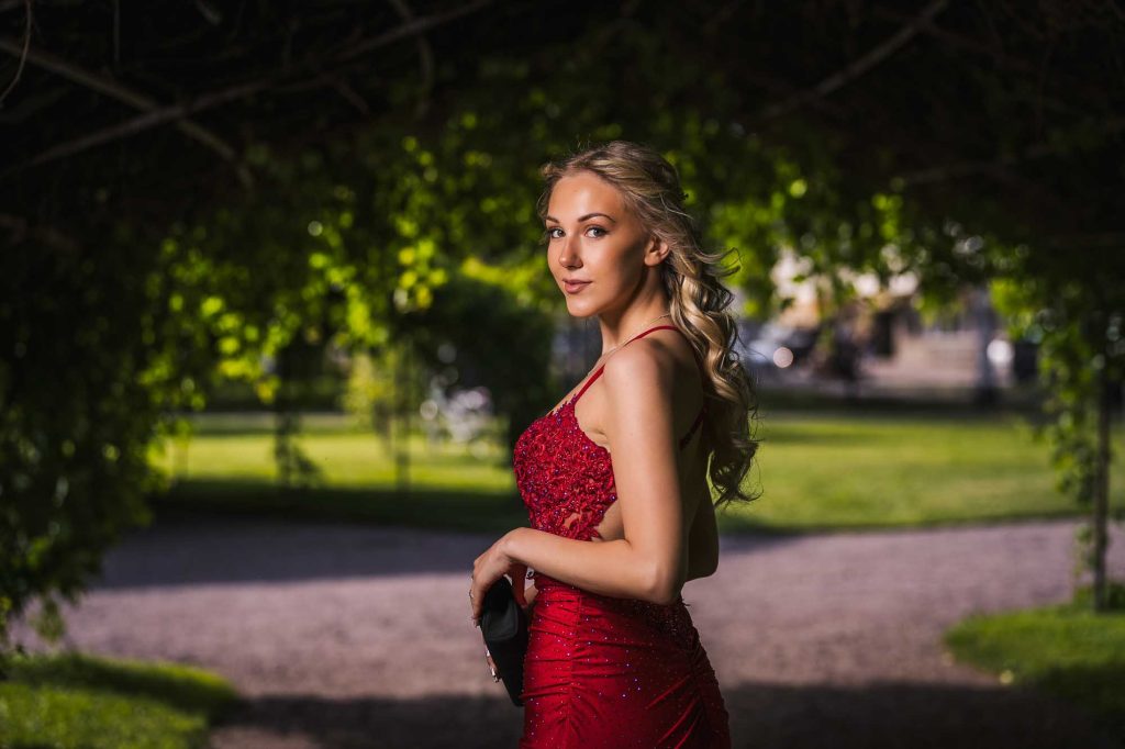 Porträtt av ung kvinna i röd klänning på studentagen.
