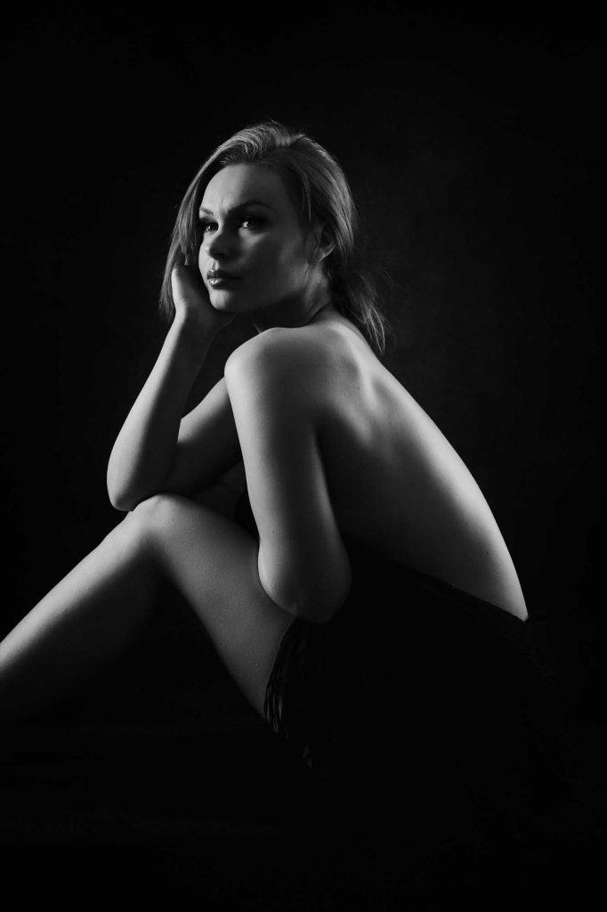 Ung kvinna halv avklädd sitter på bänk.