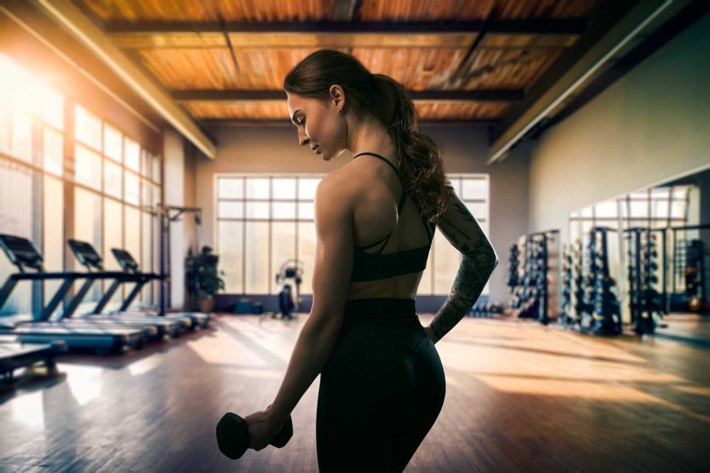 Ung kvinna lyfter hantel i ett gym