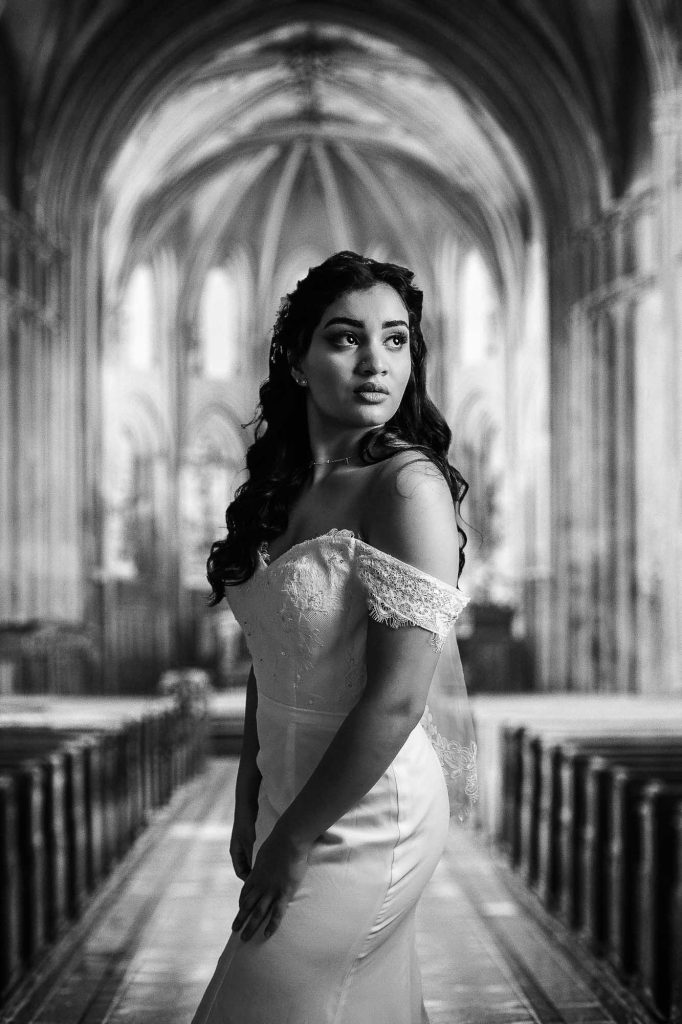 Porträtt av ung kvinna i bröllopsklänning i en kyrka.