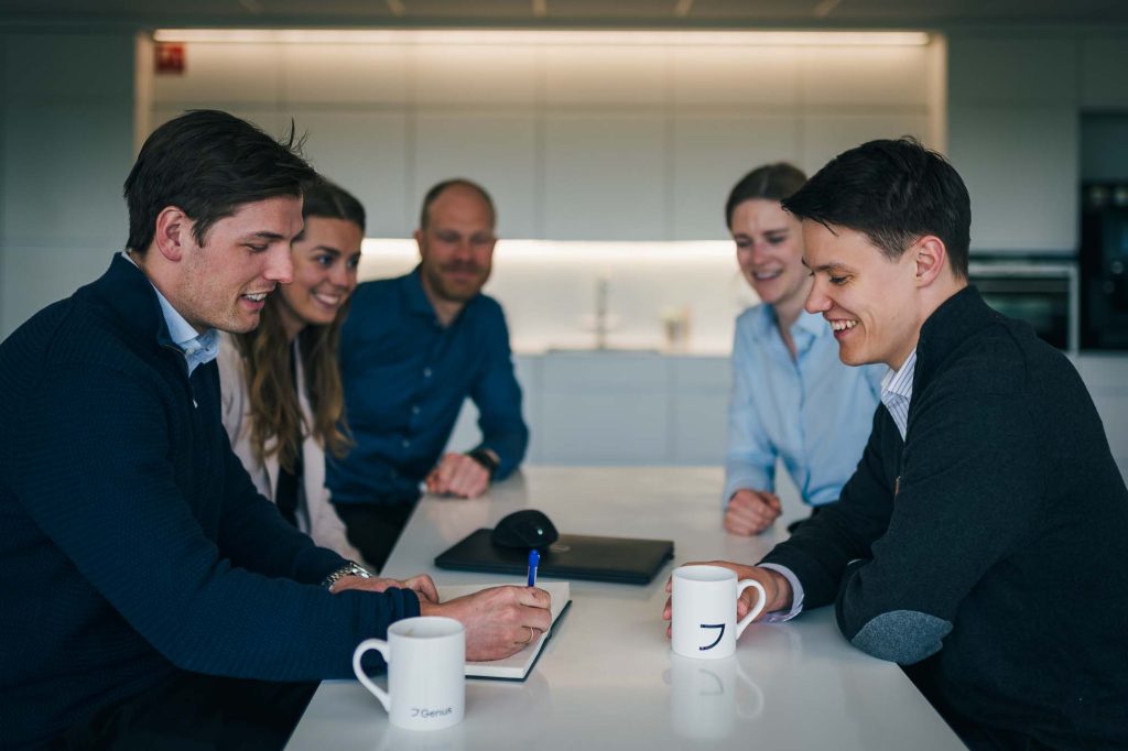Fem medarbetare sitter och diskuterar över en kopp kaffe.