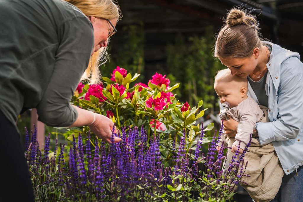 Bild av kund som visar mor och barn färgglada blommor på Högvalta handelsträdgård.