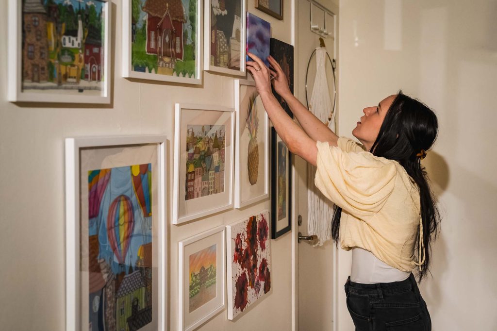 Julia hänger tavla på väggen på Julias hörna i Jössefors Folkets hus.