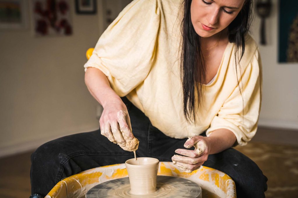 Bild av fokuserad Julia som häller vatten över sin kopp på Julias hörna i Jössefors Folkets hus.