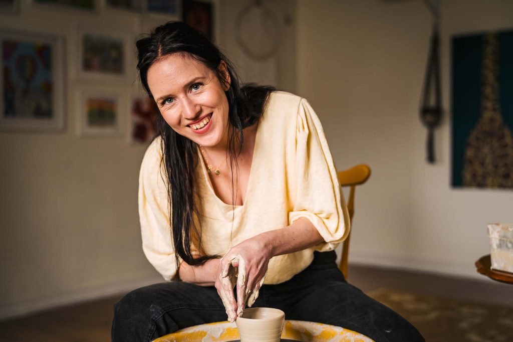 Bild av glad Julia som drejar keramik kopp på Julias hörna i Jössefors Folkets hus.