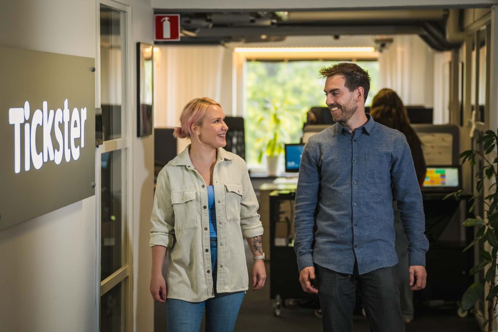 Två medarbetare går i korridor och diskuterar på Tickster i Arvika.