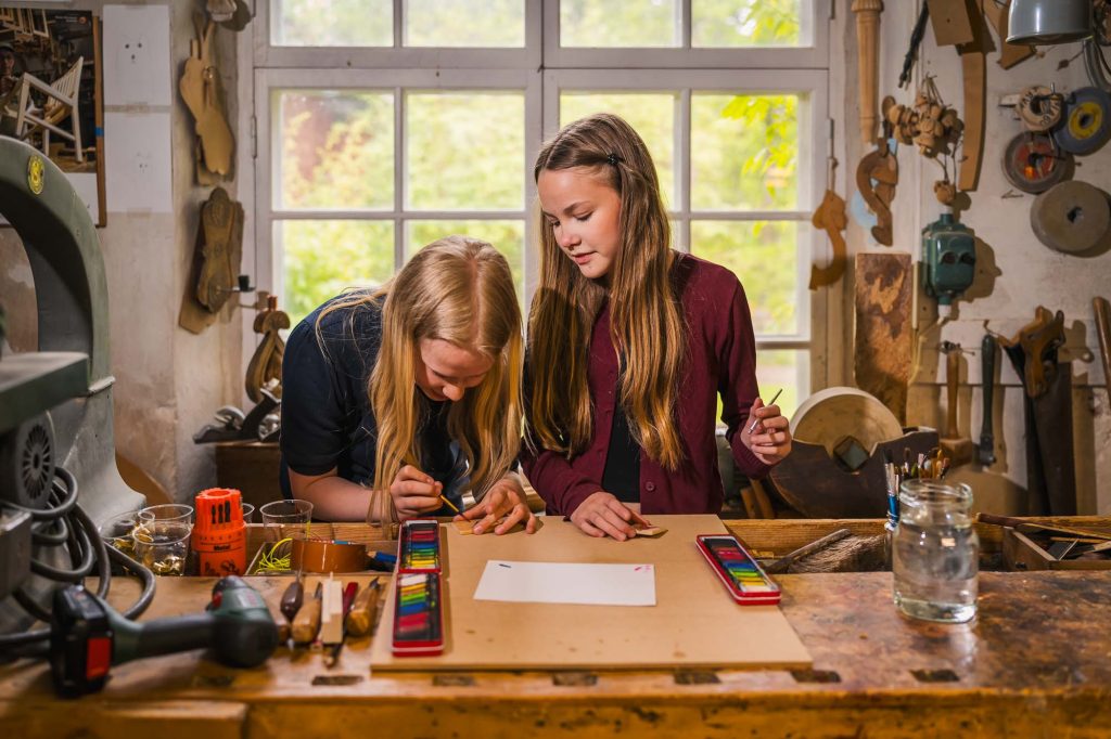 Två små tjejer är fullt fokuserade på skapande verksamhet på skaparverkstaden på Rackstadmuseet.