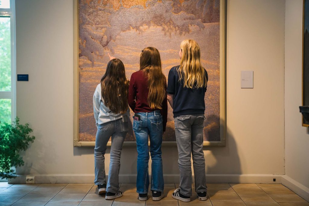 Tre små tjejer står framför målning på Rackstadmuseet i Arvika.