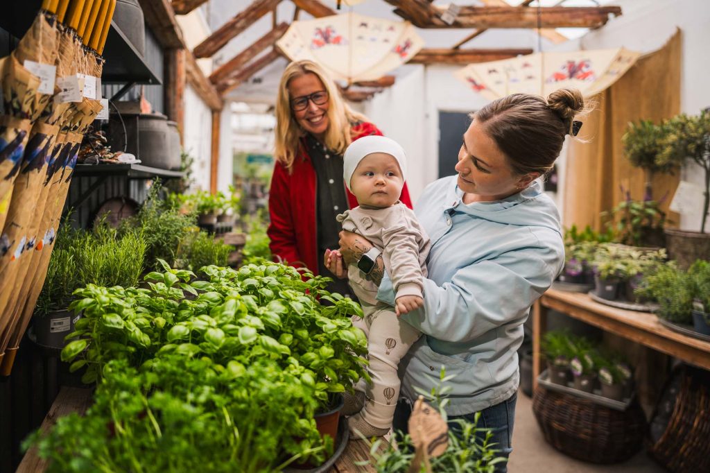 Bild av barn och mor och annan kund bland blommor på Högvalta handelsträdgård.