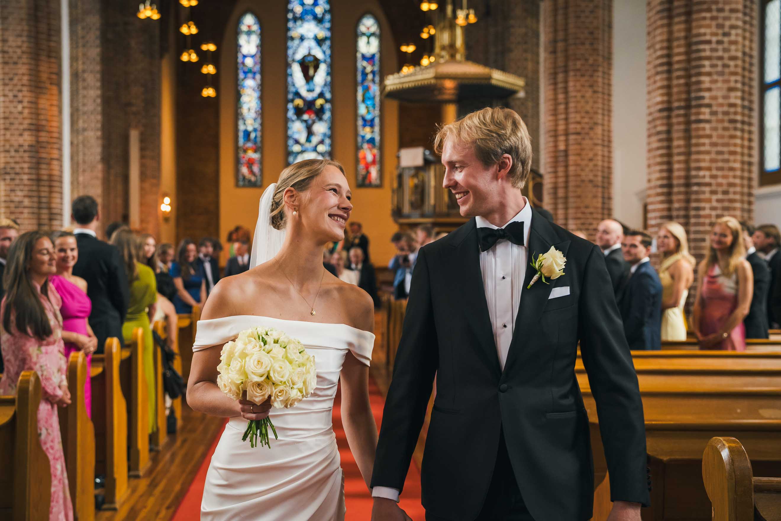 Nygift bröllopspar tittar på varandra samtidigt som de går ut ur kyrkan.