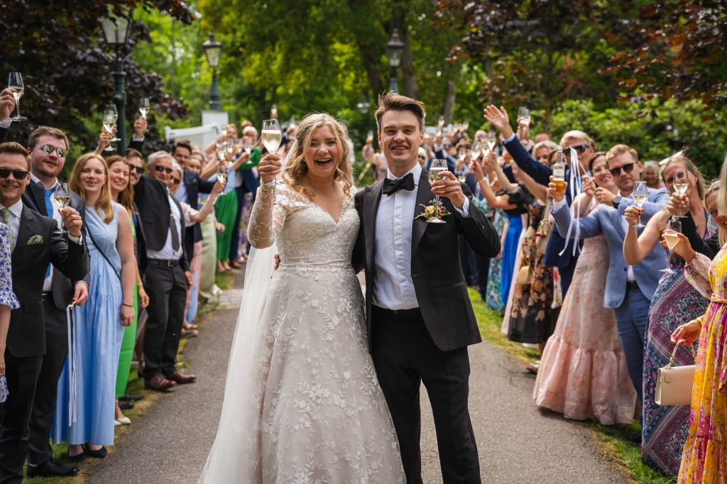 Brudparet höjer champagneglaset och skålar tillsammans med alla bröllopsgäster