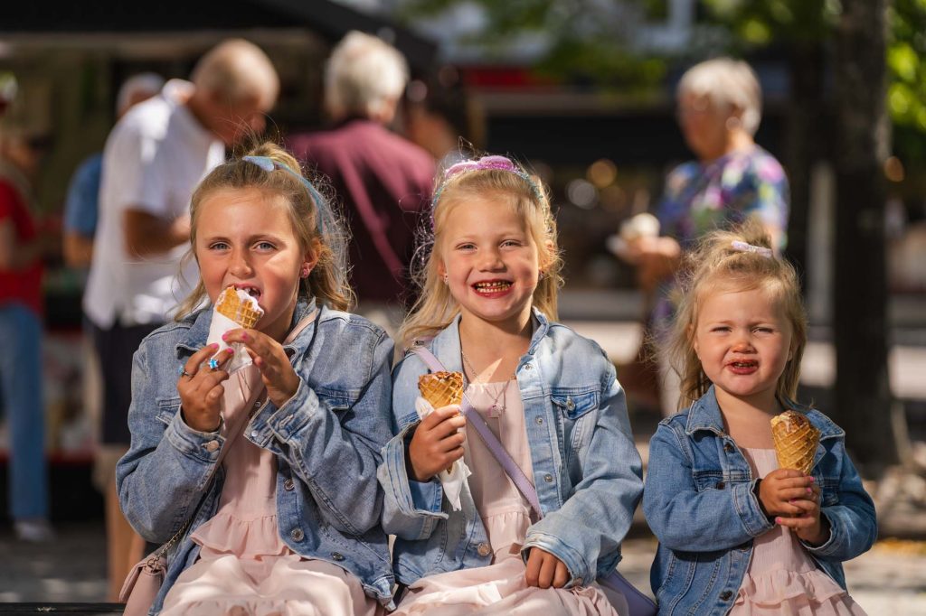 Tre små systrar sitter och äter glass på torget i Arvika.
