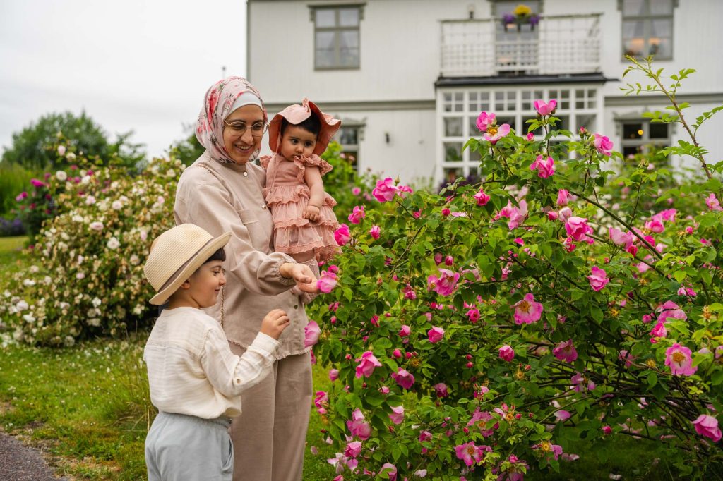 Mor med sina två barn bland rosorna utanför Rackstadmuseet.