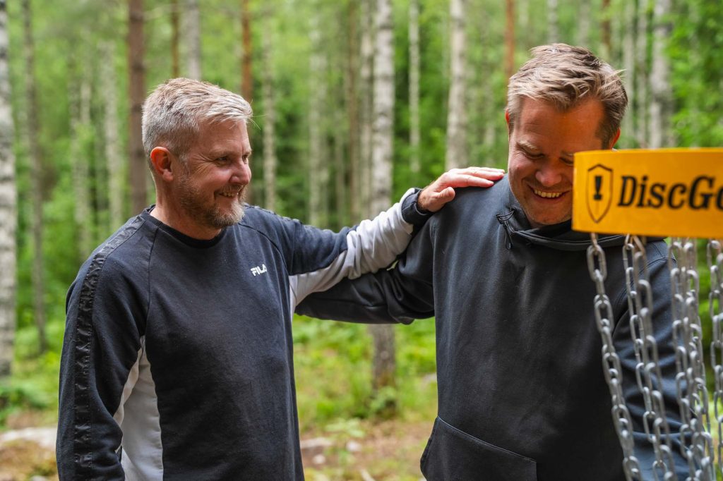 Den ena killen gratulerar den andre för ett bra kast när de spelar frisbeegolf på Ingestrand camping i Arvika.