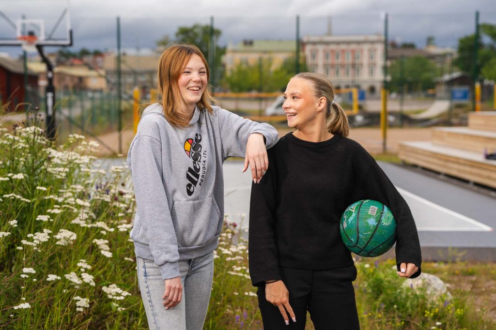 Två tonåriga tjejer har kul med basketboll i hamnområdet i Arvika.