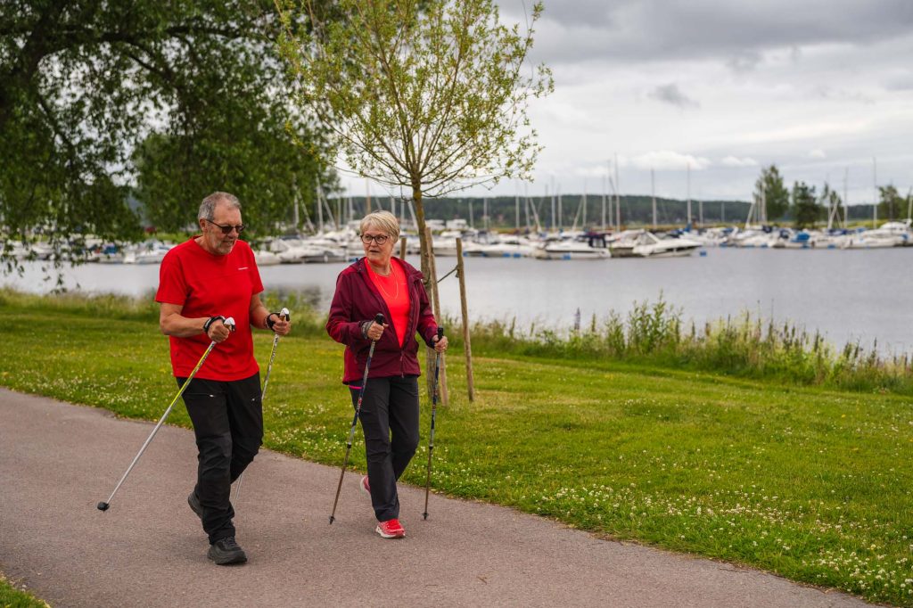 Pensionärer motionerar på den långa allén vid segelbåtshamnen i Arvika.