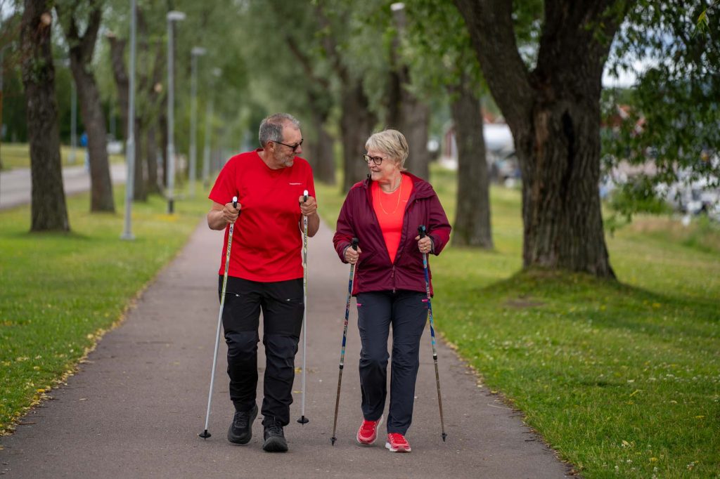 Äldre par går stavgång på promenadstråket vid Kyrkviken i området Strand.