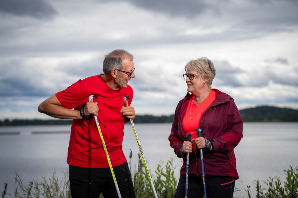 Äldre par vilar på stavarna efter motion vid Kyrkviken i Arvika.