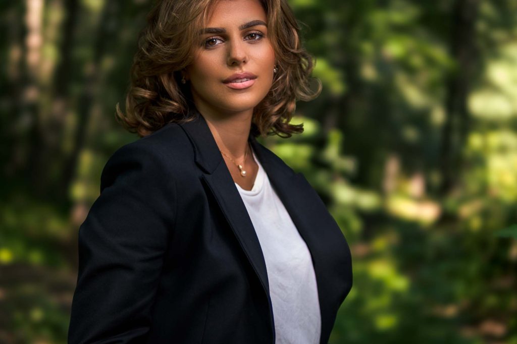 Ung kvinna i skogen iklädd kostym.