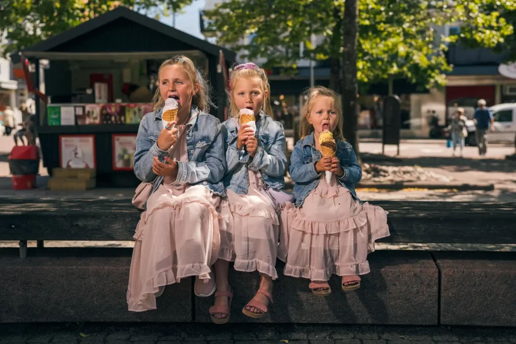 Sommarkänsla på Torget i Arvika där barn njuter av glass i solskenet. Bilden visar den levande och familjevänliga stadskärnan i Värmland, en del av Arvikas platsvarumärke.