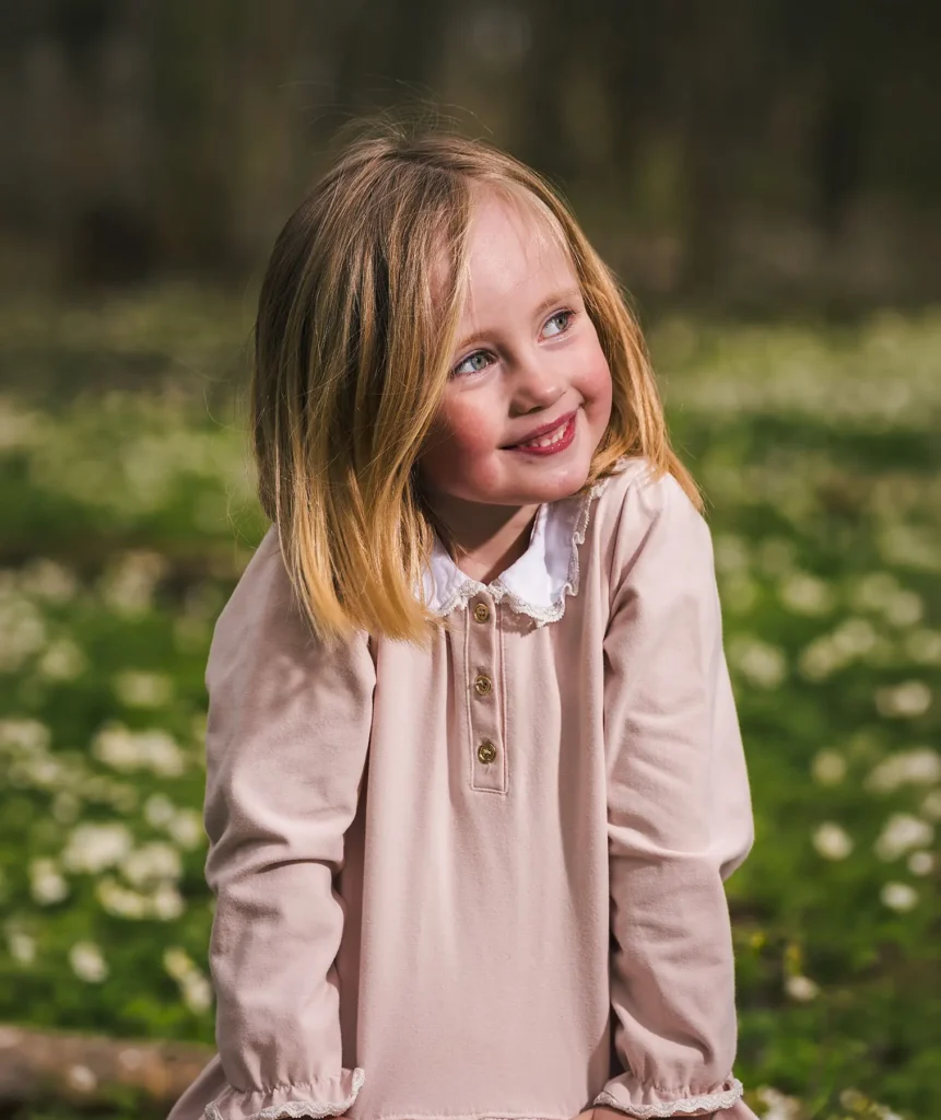 Nära porträtt på en glad flicka som tittar åt sidan under en barnfotografering utomhus i Kil.