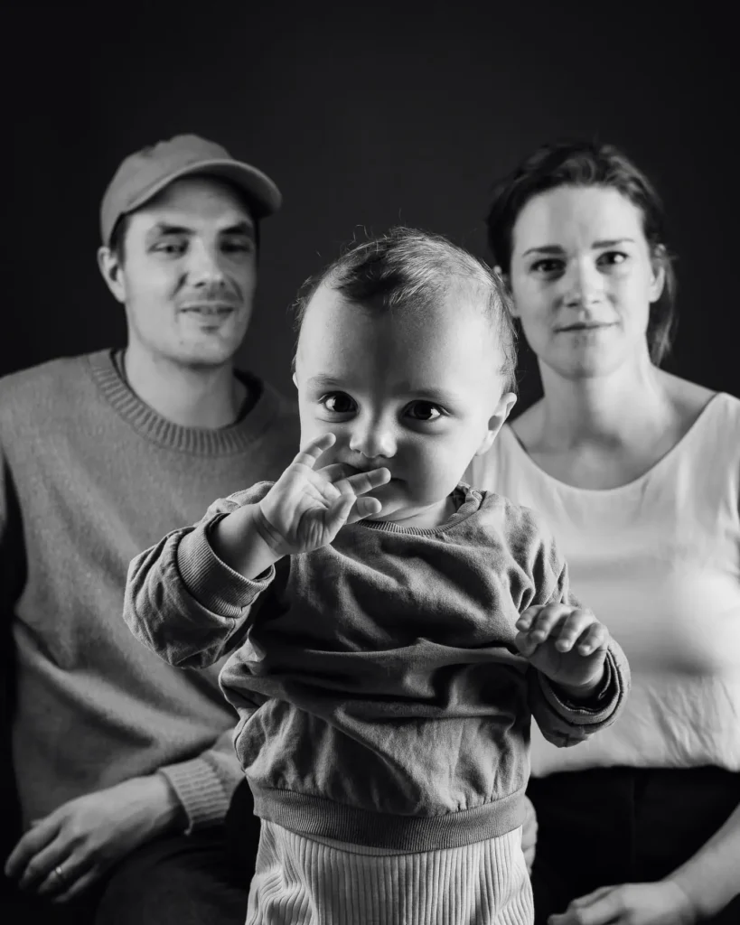 Ett svartvitt studioporträtt på en familj med ett litet barn i förgrunden, fotograferad i en studio i Arvika.
