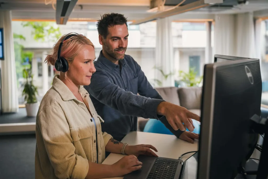 Två kollegor samarbetar vid en skärm i en modern kontorsmiljö, fotograferad av företagsfotograf i Värmland.