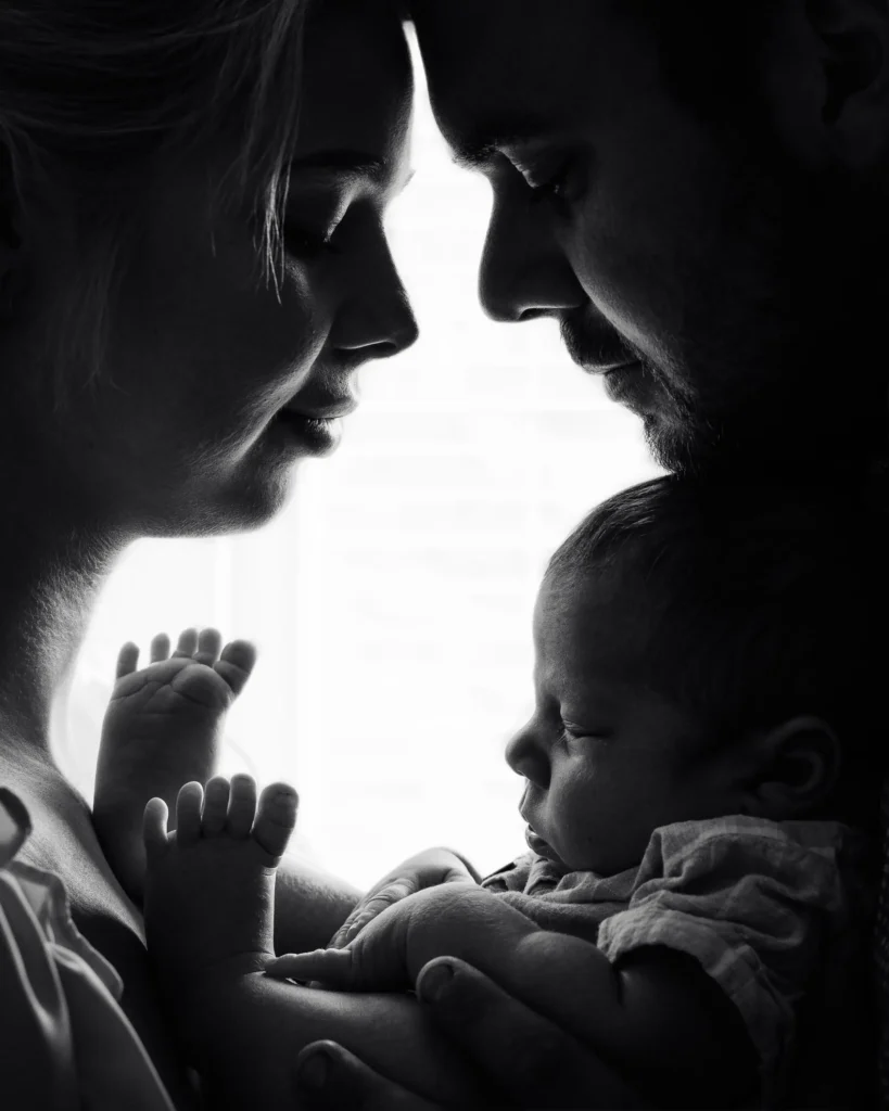 Stämningsfullt svartvitt siluettporträtt av föräldrar som håller sin nyfödda bebis i Pixpeps studio i Arvika.